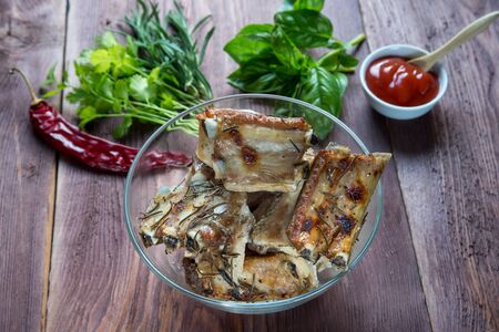 Delicious barbecued ribs  served with fresh herbs on glass dish in a country kitchenの写真素材