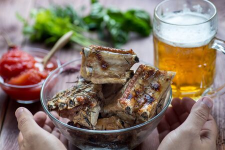 Delicious barbecued ribs  served with fresh herbs on glass dish in a country kitchenの写真素材