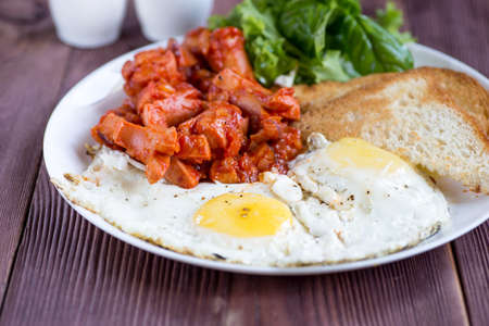 English breakfast with  sausage in tomato sauce, fried egg, toast.の写真素材