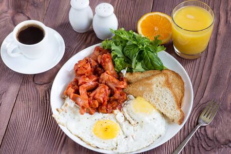 English breakfast with  sausage in tomato sauce, fried egg, toast, coffee and orange juiceの写真素材