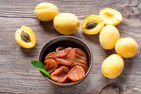 Fresh apricots on a dark wooden background. Dried apricots in the bowl.の写真素材