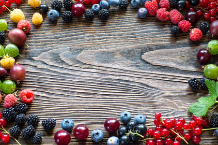 Berries on Wooden Background. Summer or Spring Organic Berry over Wood. Strawberries, Raspberries, Blueberry,Gooseberry, blackberry currant.. Agriculture, Gardening, Harvest Conceptの写真素材