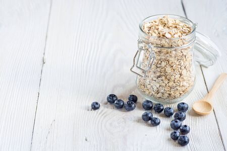 Mason jar of oat flake, berries and fresh milk on white background - health and diet concept (with easy removable sample text)の写真素材