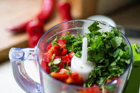 Blender with fresh bell pepper and cilantro on and kitchen table.の写真素材