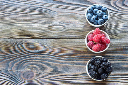Berries in bowls on wooden background. Raspberries, Blueberries, Blackberry  Health, Diet,...