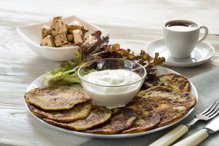 Zucchini corn fritters with yogurt sauce on a white wood background. Selective focusの写真素材