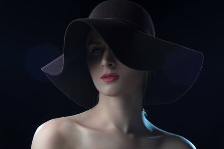 High fashion portrait of elegant woman in black  hat . Studio shot