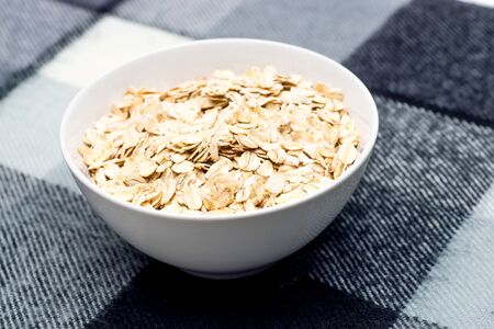 Food. Dry rolled oat flakes oatmeal in brown ceramic bowl. Top viewの写真素材
