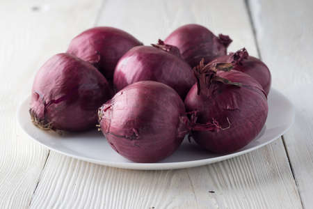 Red Onion on white plate on a wood backgroundの写真素材
