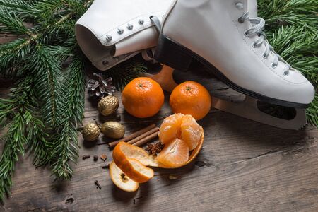 Ice skates for figure skating with tangerine and fir tree branch hanging on rustic background. Christmas decoration.の写真素材
