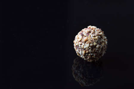 Delicious chocolates, rolled oats, pecan nuts, dates, coconut flakes on black background with reflectionの写真素材