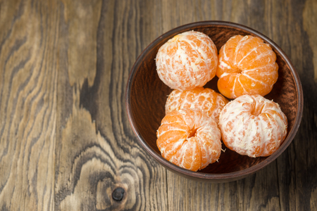 Peeled tangerines in wooden plate. Dried  citrus fruit  on a wooden tableの写真素材