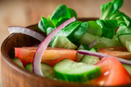 Healthy eating, organic food and diet concept - close up of fresh green salad with spinach, cucumber and tomato on wooden tableの写真素材
