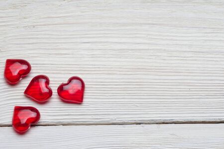 Love for Valentine's day: red beads with a shape of a heart on wood plank background