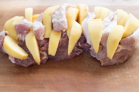 Photo of raw meat. Pork neck stuffed  with pumpkin on wooden boardの写真素材