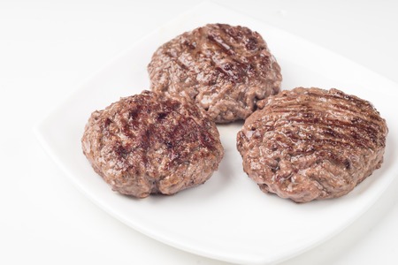 Food: three fresh uncooked homemade cutlet on a plate, isolated on white backgroundの写真素材