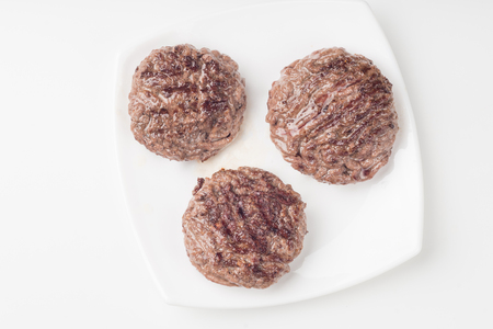 Food: three fresh uncooked homemade cutlet on a plate, isolated on white background