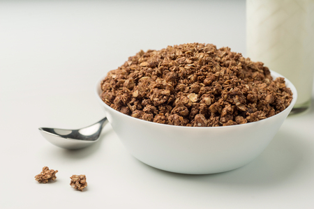 Bowl of oat flake with raisins, glass of  milk and spoon full of muesli on white background - health and diet conceptの写真素材