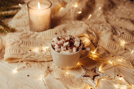 Cup of hot cocoa with marshmallows a against rustic background with Christmas fir branches of bokeh. Perfect winter time treat. Toned image. Soft focus.の写真素材