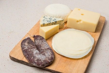 Close up of cutting board with sliced salami, and assorted cheese.の写真素材