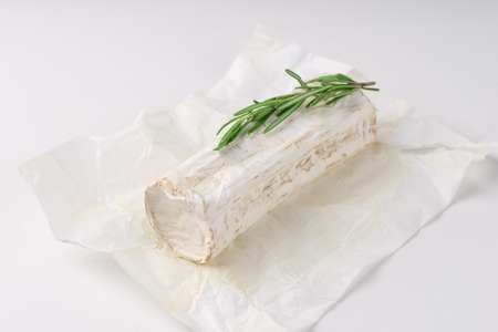 Slices goat cheese and goat cheese piece with rosemary on white background. Culinary cheese eating.の写真素材
