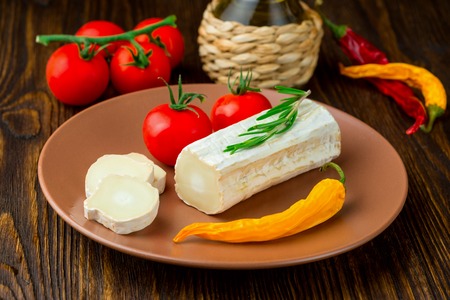 Fresh greek goat cheese  on clay plate with hot pepper, tomato and rosemary.の写真素材