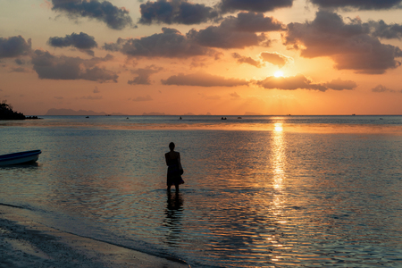 Woman silhouette looking at the sea sunset time, dark clouds.の写真素材