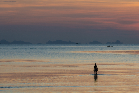 Fisherman in the kayak on the ocean in sunset sky.Silhouettes of human is paddling on kayak at sea with city views when sunset. Silhouette of a man kayaking in the open sea at sunset.の写真素材