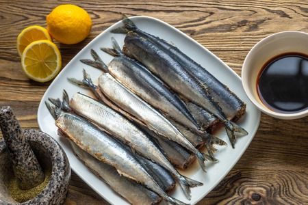 Appetizing saury fish in kitchen on plate and wooden board. Smoked saury.Smoked fish with spiceの写真素材