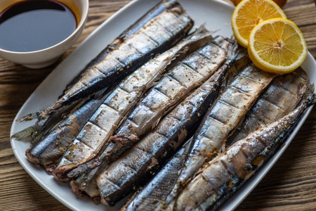 Appetizing saury fish in kitchen on plate and wooden board. Smoked saury. Smoked fish with spiceの写真素材