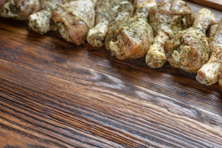 Chicken legs with spices and herbs ready for cooking on wooden board.の写真素材