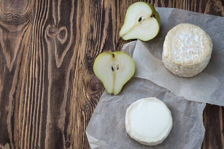 Camembert  cheese and goat cheese on wooden table Pieces of various cheeses and pears on white paper.の写真素材