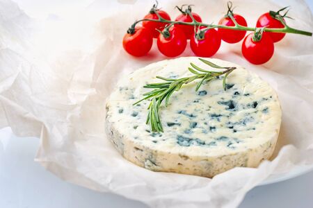 Tasty blue cheese with rosemary and cherry tomato  tomato, paper on white table.の写真素材