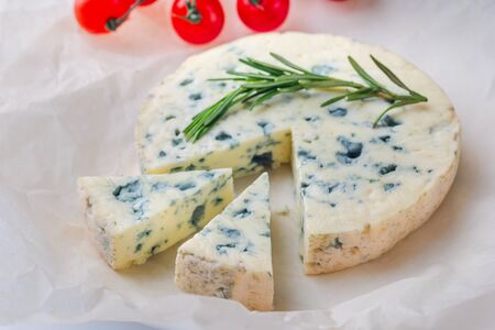 Tasty blue cheese with rosemary and cherry tomato  tomato, paper on white table.の写真素材
