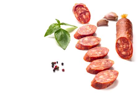 Slices of salami sausage, with basil leaf, pepper and garlic isolated on white background.の写真素材