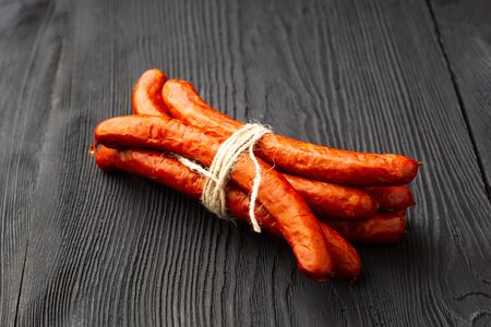 Air dried pork sausage stack of smoked meat, on black wooden texture.の写真素材