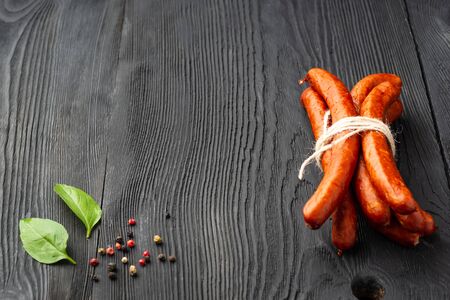 Air dried pork sausage stack of smoked meat, on black wooden texture.の写真素材