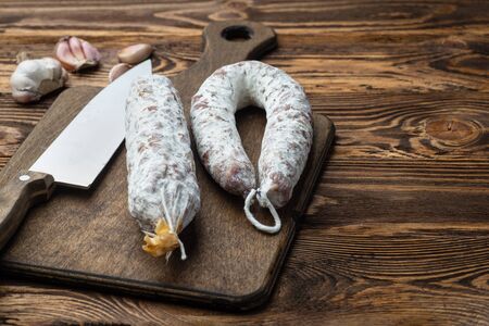 Traditional sausage and sausage with mold. Sliced sausage salami and knife on wooden board with garlic. Close-up. top viewの写真素材