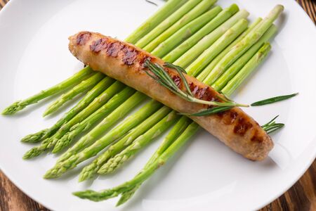 Grilled sausage with Asparagus and rosemary in a white plate on a dark background. Breakfast, healthy foodの写真素材