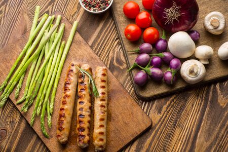 Fried sausages with sauces and vegetables on a wooden serving Board. Concept of healthy food. Top view with copy spaceの写真素材