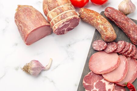 Top view of sliced sausage decorated with tomato and chili pepper. Sausage on grey stone, flat lay...