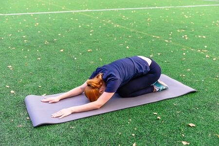 Yoga outdoor. Young woman doing yoga exercises,  practicing yoga on the grass. Concept of healthy lifestyle and relaxation.の写真素材