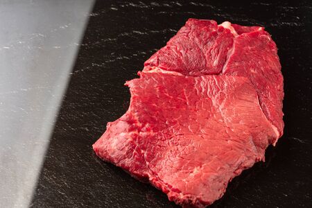 Fresh raw  beef meat. Piece of fresh red meat with black stone background.の写真素材