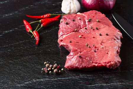 Raw uncooked meat steak striploin new york on a stone board with Chilli and pepper top view, horizontalの写真素材
