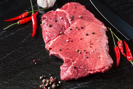 Raw uncooked meat steak striploin new york on a stone board with Chilli and pepper top view, horizontalの写真素材