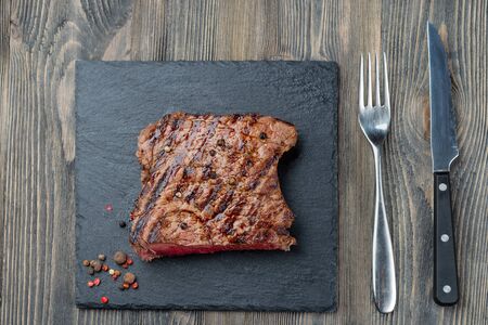 Sliced medium rare grilled Beef steak Ribeye with pepper on meat black stone board on dark wooden backgroundの写真素材