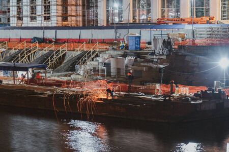 A construction worker doing welding work on the under-construction. Water reflections.の写真素材