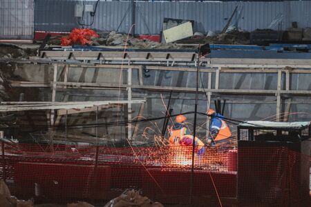 Professional worker cuts metal by electric saw. Fountain of sparks. Fire safety at construction site. Danger and hard work.の写真素材