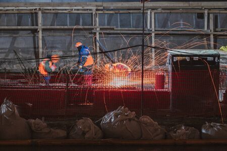 Professional worker cuts metal by electric saw. Fountain of sparks. Fire safety at construction site. Danger and hard work.の写真素材