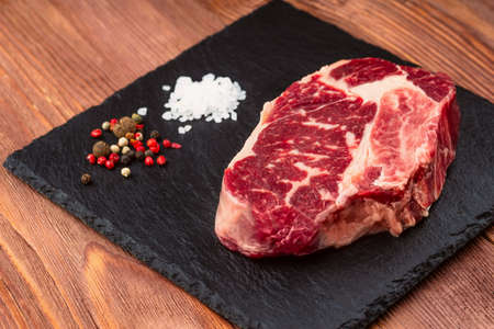Fresh raw Prime Black Angus beef steaks on stone board: Striploin, Rib Eye. Top view. On a dark wood backgroundの写真素材